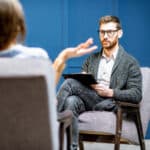 Psychologin hört einer Klientin während einer Coaching-Sitzung aufmerksam zu; Fokus auf die Unterstützung bei der Bewältigung von Kindheitstraumata durch psychologisches Coaching.